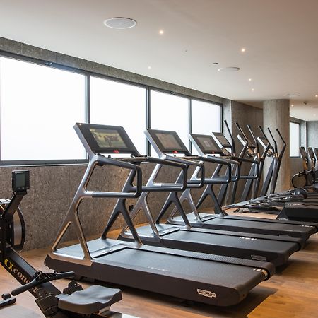 巴塞罗那索菲亚酒店-凯悦无限精选 外观 照片 The photo shows a modern gym space featuring several pieces of exercise equipment. In the foreground, there are treadmills, while in the background, there are elliptical machines lined up against large windows that provide natural light. The flooring