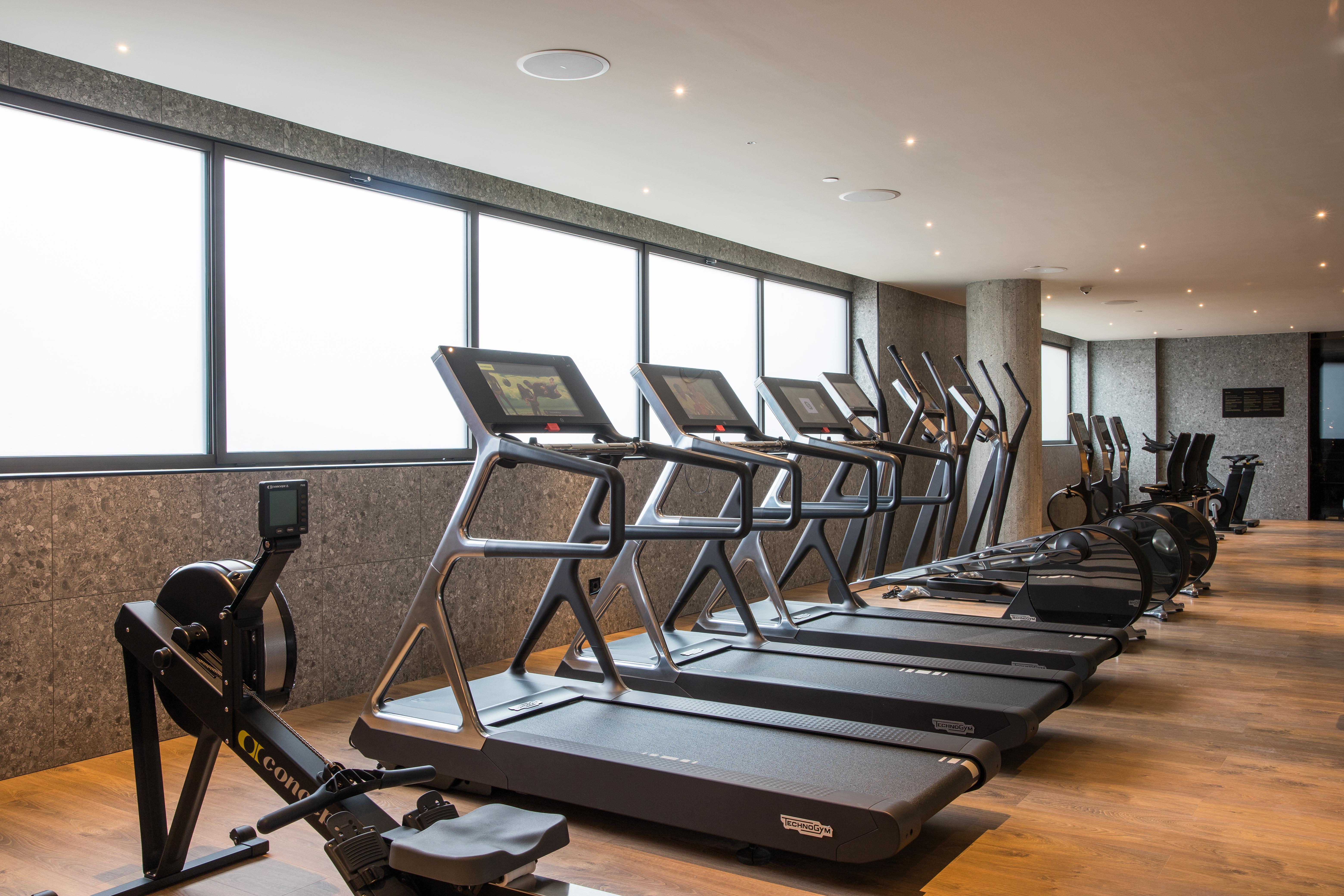 巴塞罗那索菲亚酒店-凯悦无限精选 外观 照片 The photo shows a modern gym space featuring several pieces of exercise equipment. In the foreground, there are treadmills, while in the background, there are elliptical machines lined up against large windows that provide natural light. The flooring