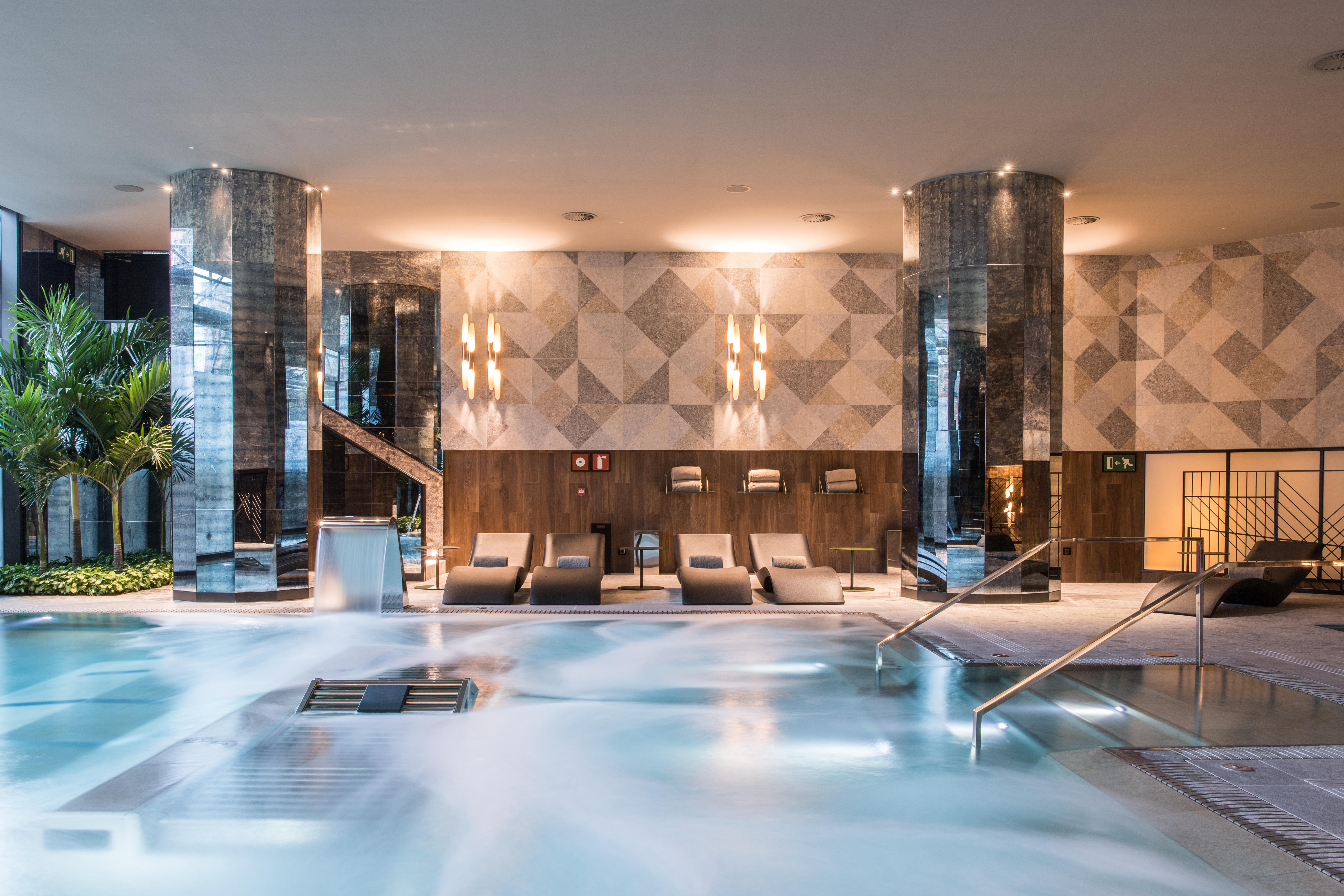 巴塞罗那索菲亚酒店-凯悦无限精选 外观 照片 The photo shows a sophisticated spa area featuring a large, inviting pool with a calm, relaxing atmosphere. The pool area is surrounded by elegant columns and has a modern design. There are comfortable lounge chairs positioned nearby, and the lightin
